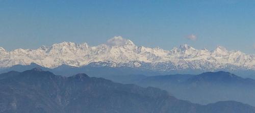 a mountain range with snow covered mountains in the distance at The Bugyal in Kanatal