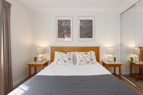 a bedroom with a bed with two tables and two windows at Eliza's Lookout in Perth