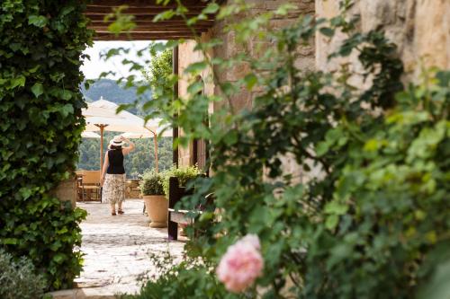 a woman walking down a walkway with an umbrella at La Torre del Visco - Relais & Châteaux in Fuentespalda