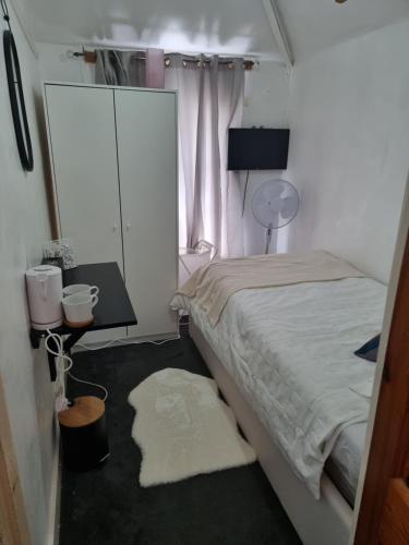 a bedroom with a bed and a table and a window at Comfortable Single Room in Welling