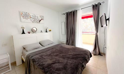 een slaapkamer met een bed en een raam bij los Gigantes Jardines del Mar in Puerto de Santiago