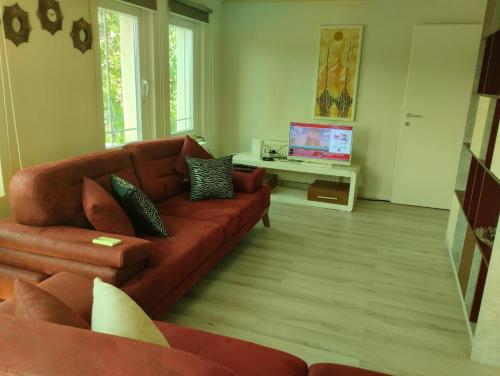 a living room with a brown couch and a tv at Villa Nënë Terezës in Pristina