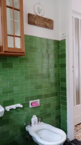 a green tiled bathroom with a sink and a clock at Romantic Casa Rurale Le Masche in Rivara