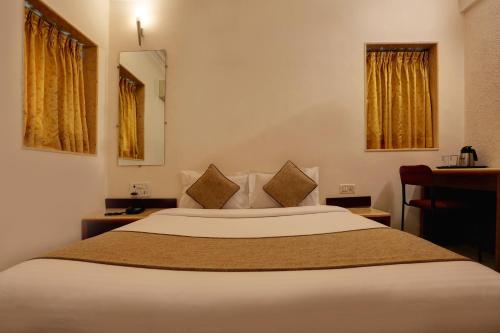 a bedroom with a large white bed with brown pillows at Accord Hotel in Mumbai