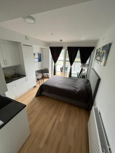 een slaapkamer met een zwart bed en een keuken bij Koselig studioleilighet in Jessheim