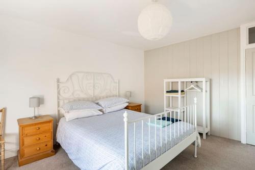 a bedroom with a white bed and a night stand at Kingfisher Cottage - Woodbridge in Woodbridge