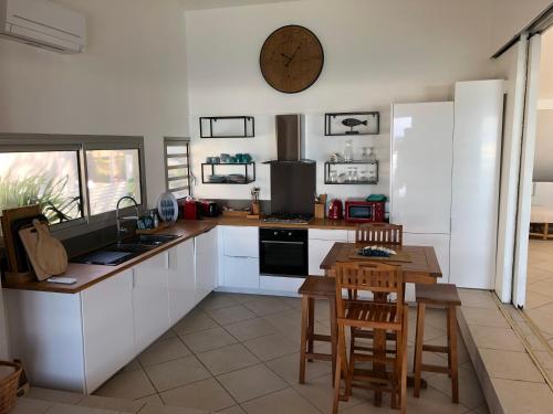 a kitchen with white cabinets and a table and a clock on the wall at vert lagon in Saint-Pierre