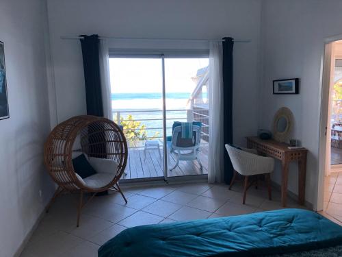 ein Schlafzimmer mit einem Balkon mit einem Bett und einem Stuhl in der Unterkunft vert lagon in Saint-Pierre