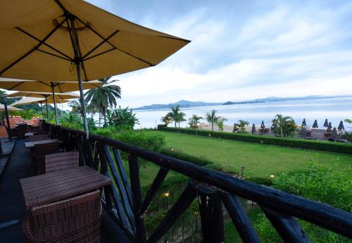 a balcony with chairs and an umbrella and the water at Divine Resort & Spa in Kampala
