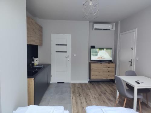 a white kitchen with a table and a tv at Apartamenty na Rynku Tarnów in Tarnów