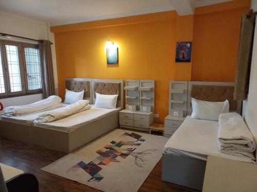 2 camas en una habitación con paredes de color naranja en Nepal christian guest house, en Pātan