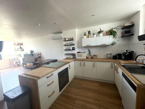 Il comprend une cuisine avec des placards blancs et du parquet. dans l'établissement Joli duplex de 75m2 à 10mn à pieds de la plage, au Lavandou
