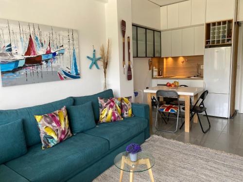 sala de estar con sofá azul y cocina en Hanah Apartment - Gjiri Lalzit Lura 3, en Mullini i Danit