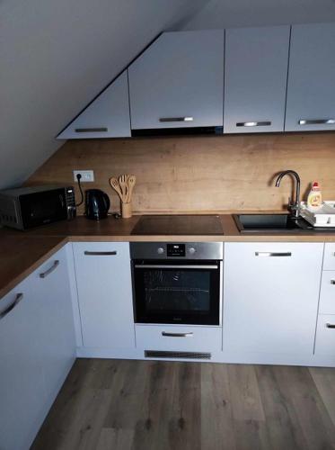 a kitchen with white cabinets and a stove top oven at Apartmány Karolin in Uhorská Ves