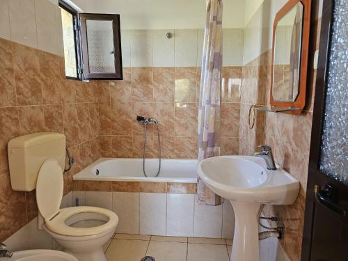 a bathroom with a toilet and a sink and a tub at Sokol Guest House in Velipojë