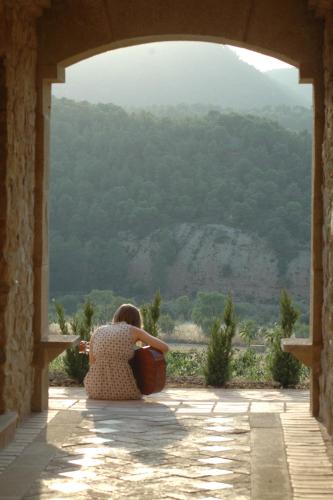 a woman sitting in an archway looking out at a mountain at La Torre del Visco - Relais & Châteaux in Fuentespalda
