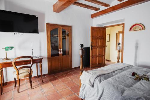 a bedroom with a bed and a desk and a tv at Masia Can Viver - Olive oil tourism B&B in Bigues i Riells