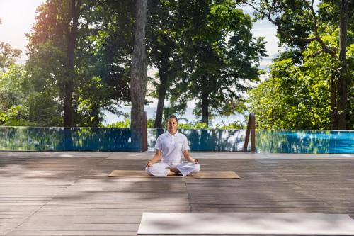 a man sitting in a yoga pose on a yoga mat at Taj Exotica Resort & Spa, Andamans in Havelock Island