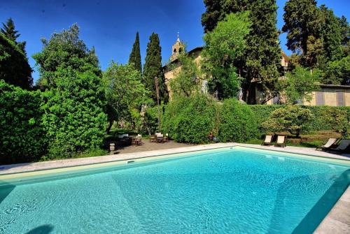 una piscina en un patio con árboles en Castello di Montegufoni by PosarelliVillas en Montagnana Val di Pesa