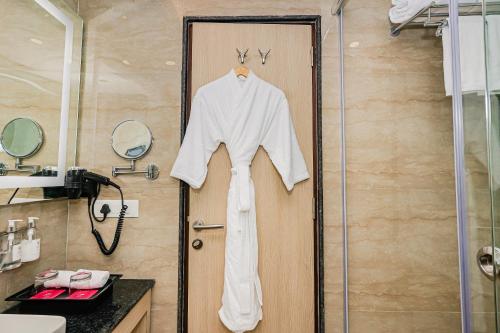 a robe hanging on a door in a bathroom at Regenta Inn Luxinna Heights Mcleodganj in Dharamshala
