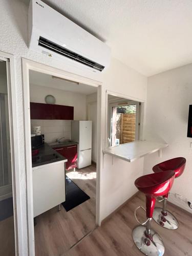 eine Küche mit einer Theke und einem roten Stuhl in einem Zimmer in der Unterkunft Les jacinthes in Marseille