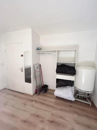 Habitación con paredes blancas, estanterías blancas y suelo de madera. en Les jacinthes, en Marsella