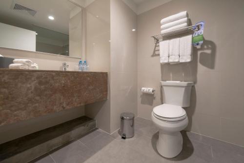 a bathroom with a toilet and a sink with towels at Holiday Inn - Lima Airport by IHG in Lima