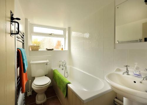 a white bathroom with a toilet and a sink at Period Cottage near Suffolk Coast and Forest in Tunstall