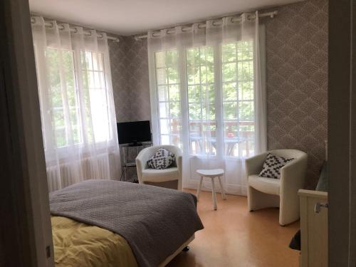 - une chambre avec un lit, deux chaises et une télévision dans l'établissement Appartement bagnoles, à Bagnoles-de-l'Orne