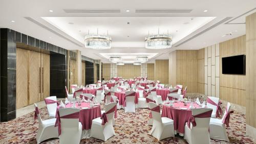 a banquet hall with tables and chairs in a room with chandeliers at Holiday Inn Gurugram Sector 90 by IHG in Gurgaon