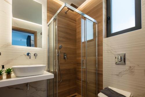 a bathroom with a sink and a glass shower at Four Horizons Luxury Villas in Kournás