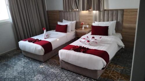 2 Betten in einem Hotelzimmer mit Blumen darauf in der Unterkunft GOLDEN NEW UMU ALQURAA Hotel in Dschidda
