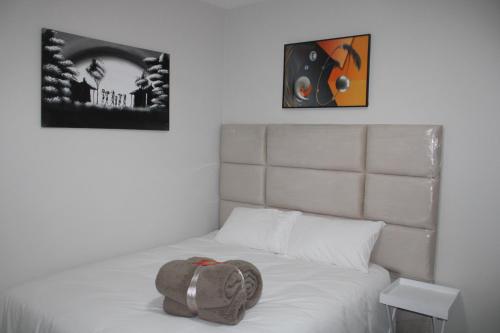 a bed with a hat sitting on top of it at Fun modern two bed apartment in fourways in Sandton