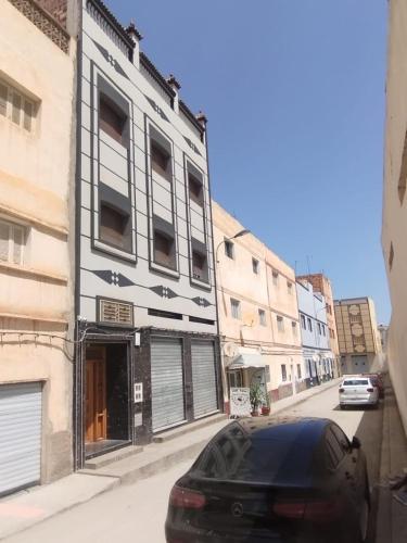 una macchina nera parcheggiata di fronte a un edificio di appartement joliment meublé pour 4/5 personnes à Imzouren 