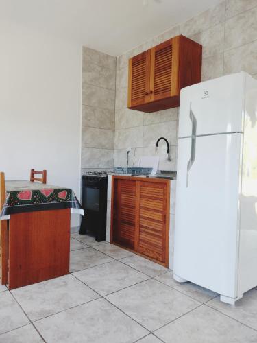 a kitchen with a white refrigerator and wooden cabinets at Suítes do Vale - Praia do Rosa in Imbituba