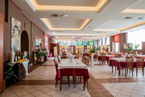 Hotel Patriarchi في أكويليا: مطعم فيه طاولات وكراسي في الغرفة