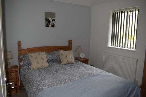 a bedroom with a bed with two pillows and a window at Upper Wood End Farm Holiday Cottages in Marston Moretaine