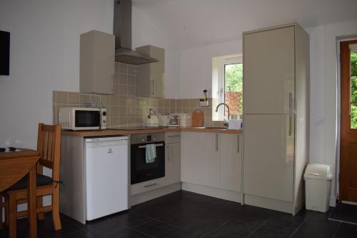 a kitchen with white cabinets and a stove top oven at Upper Wood End Farm Holiday Cottages in Marston Moretaine