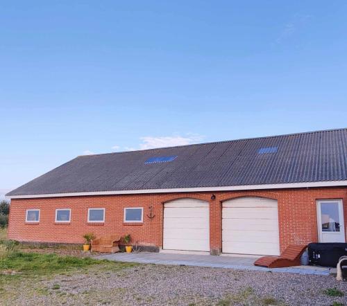 a red brick building with two white garage doors at Villa Vandkant in Thyholm