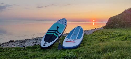 two surfboards sitting on the grass next to the water at Villa Vandkant in Thyholm