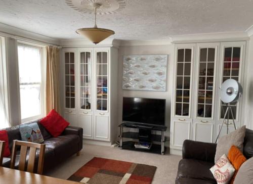 a living room with a couch and a flat screen tv at Two rivers reach in Iford