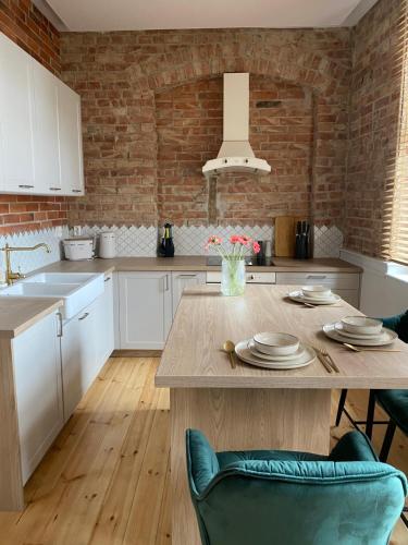 a kitchen with white cabinets and a wooden table at Apartments PSD - Wojska Polskiego 5 in Słupsk