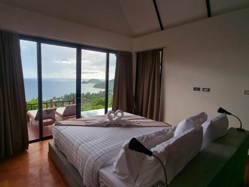 a bedroom with a bed with a view of the ocean at Taoruna Villa in Ko Tao