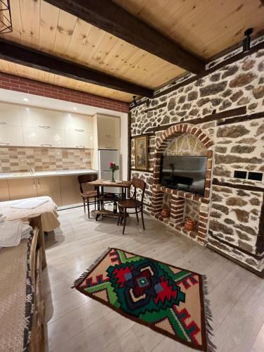 ein Wohnzimmer mit einem Steinkamin und einem Tisch in der Unterkunft Vila Gregor in Tushemisht