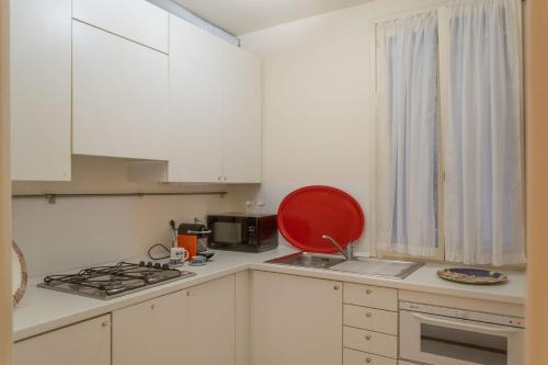 a kitchen with white cabinets and a red plate on the counter at Cianis Home San Marco - Apartment in Venice