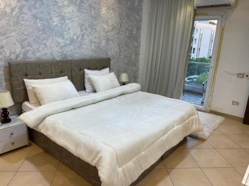 a bedroom with a large white bed with a window at شقة للايجار كمبوند زايد ديونز in Sheikh Zayed