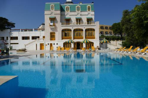a large swimming pool in front of a building at Hôtel LES MIMOSAS TABARKA in Tabarka