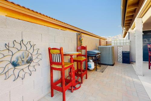 a patio with two red chairs and a table against a wall at Gold Canyon Getaway in Gold Canyon