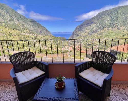 two chairs and a table on a balcony with mountains at Gardens Guest House in São Vicente