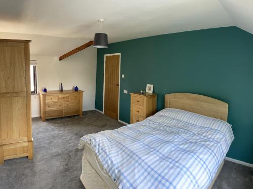 a bedroom with a bed and a blue wall at The Old Barn in St Ives